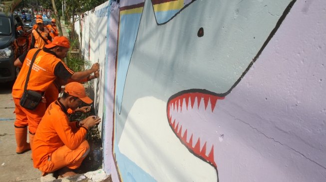 Petugas Penanganan Prasarana dan Sarana Umum (PPSU) membuat mural di tembok kawasan Setiabudi, Jakarta. [suara.com/Oke Atmaja] . 