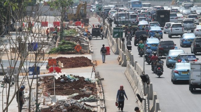 Sejumlah pekerja terlihat menyelesaikan proyek pembangunan dan penataan trotoar di Jalan Sudirman, Jakarta, Kamis (5/7/2018), menuju perhelatan Asian Games 2018. [Suara.com/Oke Atmaja]