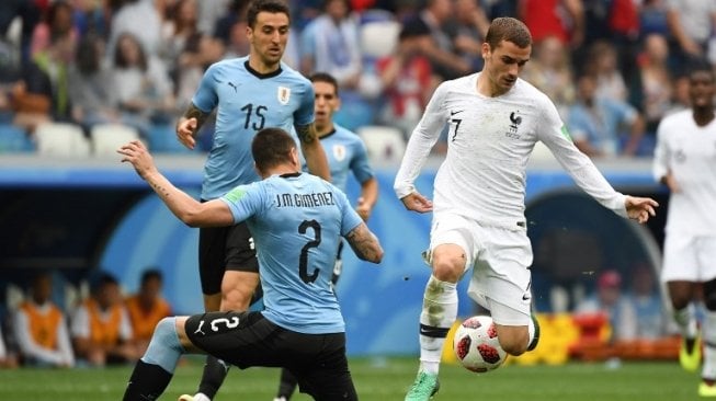 Bek Timnas Uruguay, Jose Gimenez (tengah) mencoba menghadang laju penyerang Prancis Antoine Griezmann (kanan) pada laga perempat final Piala Dunia 2018 di Nizhny Novgorod Stadium (Kirill KUDRYAVTSEV / AFP)