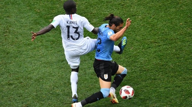 Gelandang jangkar Timnas Prancis N'Golo Kante (kiri) berebut bola dengan fullback Uruguay Martin Caceres (Johannes EISELE / AFP)