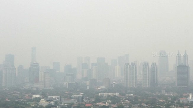 Pemandangan gedung-gedung bertingkat dan kawasan permukiman yang terhalang polusi udara di Jakarta, Jumat (13/7/2018). [Suara.com/Muhaimin A Untung]