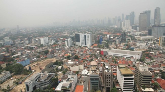 Pemandangan gedung-gedung bertingkat dan kawasan permukiman yang terhalang polusi udara di Jakarta, Jumat (13/7/2018). [Suara.com/Muhaimin A Untung]