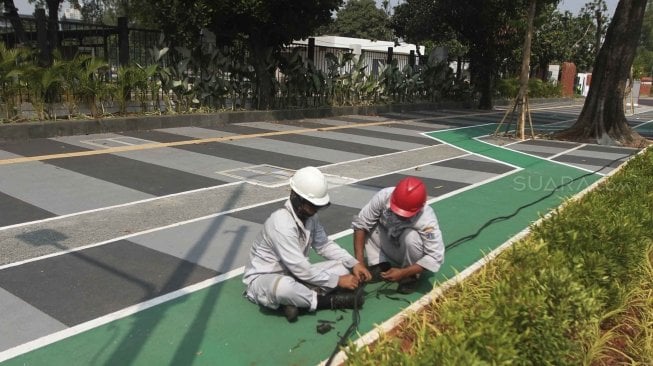 Pekerja Suku DInas Perindustrian dan Energi memperbaiki kabel perapian jaringan penerangan jalan umum di Pedestrian Kawasan Gelora Bung Karno (GBK), Jakarta, Selasa (17/7/2018).