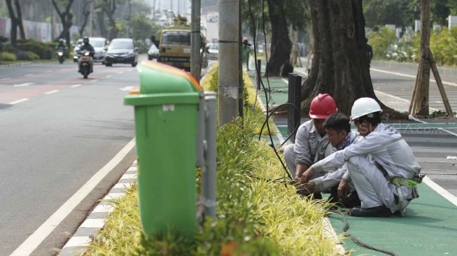 Pekerja Suku DInas Perindustrian dan Energi memperbaiki kabel perapian jaringan penerangan jalan umum di Pedestrian Kawasan Gelora Bung Karno (GBK), Jakarta, Selasa (17/7/2018).