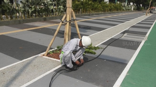 Pekerja Suku DInas Perindustrian dan Energi memperbaiki kabel perapian jaringan penerangan jalan umum di Pedestrian Kawasan Gelora Bung Karno (GBK), Jakarta, Selasa (17/7/2018).