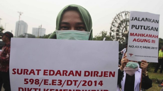 Ratusan orang yang tergabung dalam Pergerakan Dokter Muda Indonesia melakukan aksi di depan Taman Aspirasi Monas, Jakarta, Jumat (19/7). Dalam aksinya mereka meminta agar Kemeristekdi mengeluarkan ijazah Dokter yang disita.[suara.com/Muhaimin A Untung]