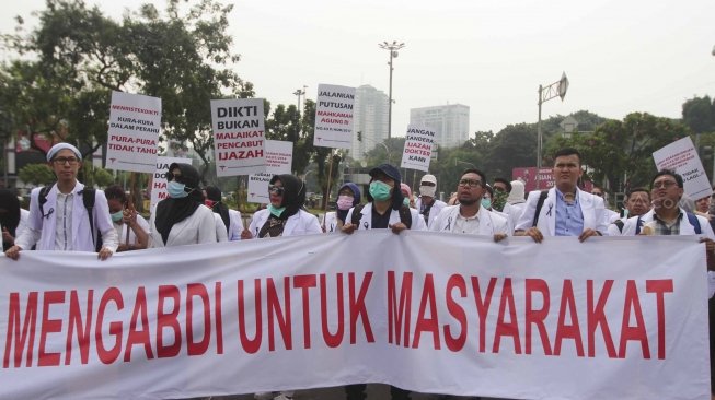 Ratusan orang yang tergabung dalam Pergerakan Dokter Muda Indonesia melakukan aksi di depan Taman Aspirasi Monas, Jakarta, Jumat (19/7). Dalam aksinya mereka meminta agar Kemeristekdi mengeluarkan ijazah Dokter yang disita.[suara.com/Muhaimin A Untung]
