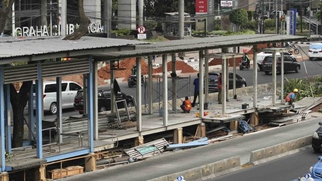 Sejumlah pekerja terlihat menyelesaikan pembangunan perluasan halte Transjakarta Gelora Bung Karno (GBK) di Jalan Sudirman, Jakarta, Jumat (20/7/2018). [Suara.com/Muhaimin A Untung]