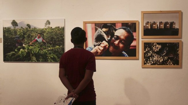 Pengunjung memperhatikan foto yang dipamerkan di Festival Kopi di Bentara Budaya, Jakarta, Minggu (22/7). [suara.com/MuhaiminA Untung]