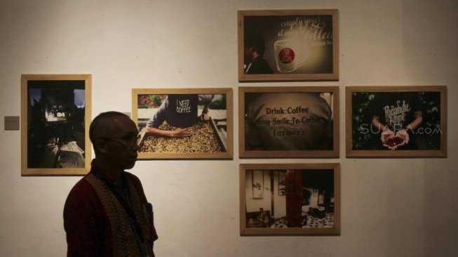 Pengunjung memperhatikan foto yang dipamerkan di Festival Kopi di Bentara Budaya, Jakarta, Minggu (22/7). [suara.com/MuhaiminA Untung]