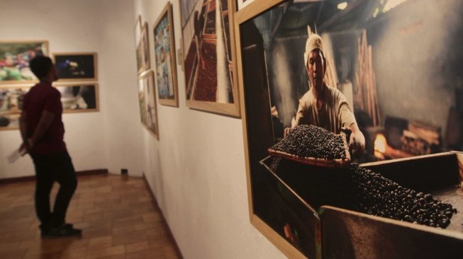 Pengunjung memperhatikan foto yang dipamerkan di Festival Kopi di Bentara Budaya, Jakarta, Minggu (22/7) .[suara.com/MuhaiminA Untung]