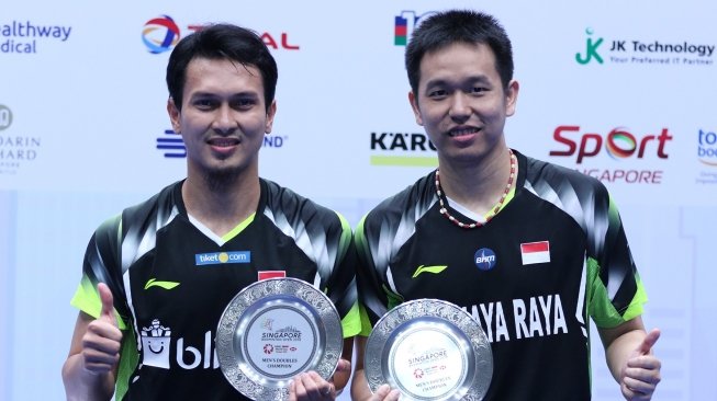 Pebulutangkis ganda putra Indonesia Hendra Setiawan (kanan) dan Mohammad Ahsan berfoto bersama usai memenangi laga final Singapura Terbuka 2018 melawan pasangan Cina Ou Xuanyi/Xiangyu usai laga final Singapura Terbuka 2018 di Singapore Indoor Stadium, Minggu (22/7). ANTARA FOTO/Humas PBSI