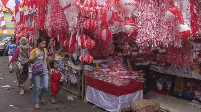 Penjual memajang bendera dan pernak-pernik bernuansa merah putih di Pasar Jatinegara, Jakarta, Senin (23/7). Bendera dan pernak-pernik yang dijual dengan harga Rp. 20 ribu hingga Rp. 500 ribu tergantung ukuran dan jenis bahan tersebut mulai marak dijual menjelang peringatan Hari Kemerdekaan Indonesia pada 17 Agustus. [Suara.com/Muhaimin A Untung]