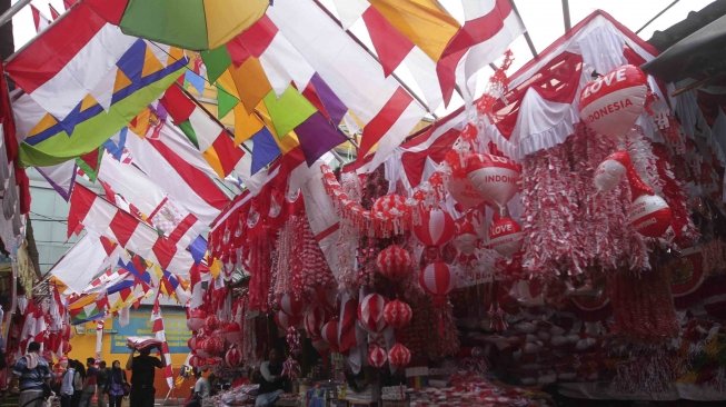 Penjual memajang bendera dan pernak-pernik bernuansa merah putih di Pasar Jatinegara, Jakarta, Senin (23/7). Bendera dan pernak-pernik yang dijual dengan harga Rp. 20 ribu hingga Rp. 500 ribu tergantung ukuran dan jenis bahan tersebut mulai marak dijual menjelang peringatan Hari Kemerdekaan Indonesia pada 17 Agustus. [Suara.com/Muhaimin A Untung]