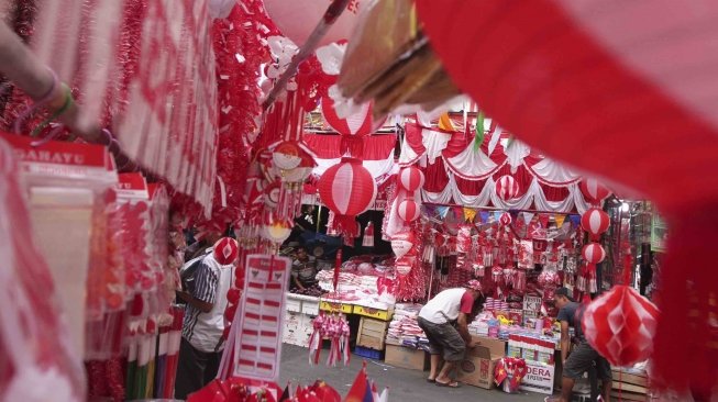 Penjual memajang bendera dan pernak-pernik bernuansa merah putih di Pasar Jatinegara, Jakarta, Senin (23/7). Bendera dan pernak-pernik yang dijual dengan harga Rp. 20 ribu hingga Rp. 500 ribu tergantung ukuran dan jenis bahan tersebut mulai marak dijual menjelang peringatan Hari Kemerdekaan Indonesia pada 17 Agustus. [Suara.com/Muhaimin A Untung]