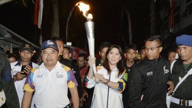 Legenda bulu tangkis Indonesia Susi Susanti  didampingi Kepala Istana Kepresidenan Tampaksiring I Dewa Gde Swarthana berlari membawa obor saat pawai obor (torch relay) Asian Games 2018 di Istana Kepresidenan Tampaksiring, Gianyar, Bali, Senin (23/7). Pawai Obor Asian Games 2018 di Pulau Dewata melintasi sejumlah lokasi antara lain Istana Kepresidenan Tampaksiring dan beberapa objek wisata di sejumlah kota/kabupaten. ANTARA FOTO/Fikri Yusuf