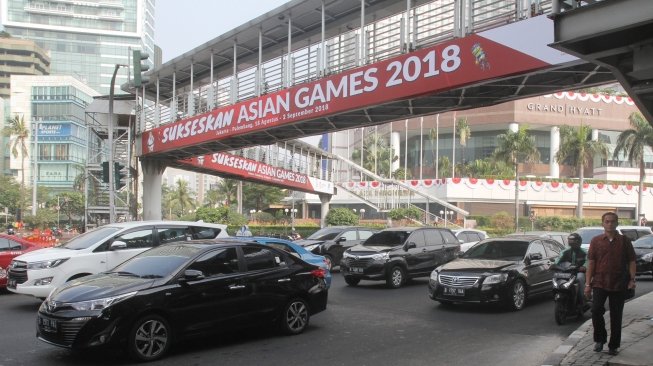 Sejumlah kendaraan melintasi Jembatan Penyebrangan Orang (JPO) di Bundaran HI, Jakarta, Rabu (25/7). Gubernur DKI Jakarta Anies Baswedan berencana akan melakukan pembongkaran JPO Bundaran HI agar tidak menganggu patung selamat datang yang dibangun untuk menyambut peserta Asian Games. Nantinya usai dirobohkan, dilokasi tersebut akan dibangun 'Pelican Crossing' untuk memudahkan pejalan kaki menyeberang jalan. [suara.com/Oke Dwi Atmaja]