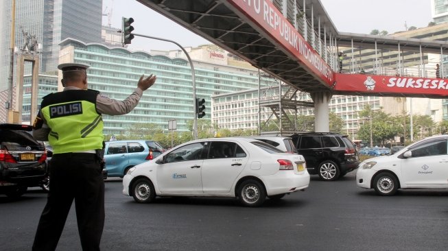 Sejumlah kendaraan melintasi Jembatan Penyebrangan Orang (JPO) di Bundaran HI, Jakarta, Rabu (25/7). Gubernur DKI Jakarta Anies Baswedan berencana akan melakukan pembongkaran JPO Bundaran HI agar tidak menganggu patung selamat datang yang dibangun untuk menyambut peserta Asian Games. Nantinya usai dirobohkan, dilokasi tersebut akan dibangun 'Pelican Crossing' untuk memudahkan pejalan kaki menyeberang jalan. [suara.com/Oke Dwi Atmaja]