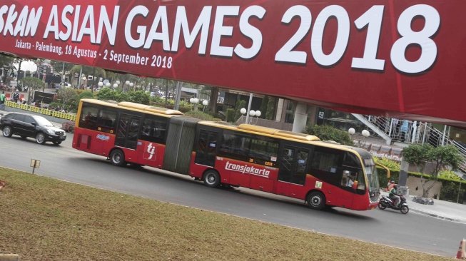 Bus Transjakarta melintas di sekitar Bunderan HI, Jakarta, Kamis (26/7). Wakil Gubernur DKI Jakarta Sandiaga Uno mengusulkan bus Transjakarta digratiskan diakhir pekan saat perhelatan Asian Games 2018  pada 18 Agustus hingga 2 September mendatang.  [suara.com/Muhaimin A Untung]