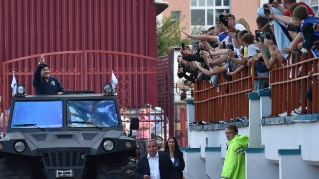 Pemain legendaris Argentina Diego Maradona berparade di kota Brest, Belarusia, 16 Juli 2018, dengan menggunakan kendaraan lapis baja [AFP]