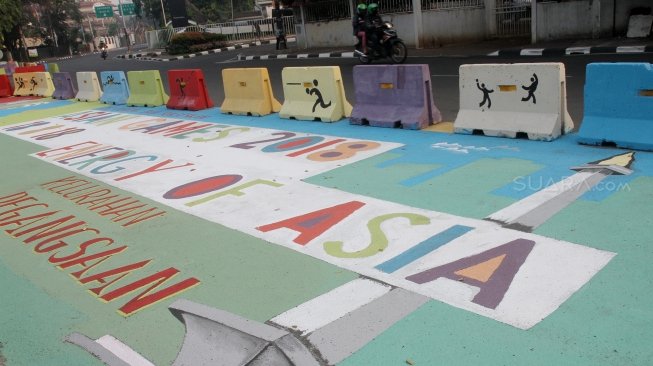 Pengendara melintas di Jalan Proklamasi yang telah dihiasi mural bertema  Asian Games, Jakarta Pusat, Jumat(27/7). Selain untuk menyambut Asian Games mural tersebut dibuat sebagai sosialisasi kepada masyarakat untuk mendukung perhelatan Asian Games 2018 Agustus mendatang