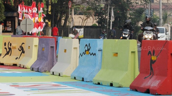 Pengendara melintas di Jalan Proklamasi yang telah dihiasi mural bertema  Asian Games, Jakarta Pusat, Jumat(27/7). Selain untuk menyambut Asian Games mural tersebut dibuat sebagai sosialisasi kepada masyarakat untuk mendukung perhelatan Asian Games 2018 Agustus mendatang