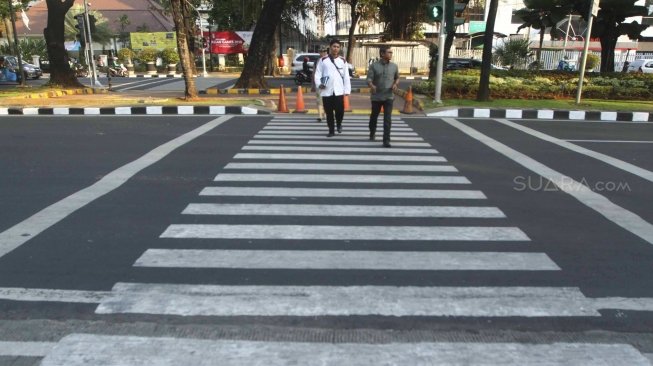 Warga menyebrang melalui Pelican Crosing di kawasan Merdeka Barat, Jakarta, Sabtu (28/7). Pemprov DKI Jakarta segera membuat pelican crossing sebagai pengganti jembatan penyeberangan orang (JPO) di Bundaran HI yang akan dirobohkan dengan alasan keindahan dan tak ramah difabel. [suara.com/Muhaimin A Untung]