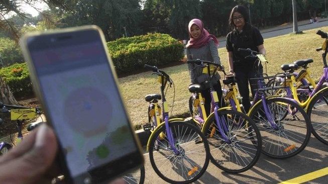 Pengunjung menggunakan sepeda dari layanan bike sharing di Monas, Jakarta, Jumat (27/7). Unit Pengelola Kawasan Monumen Nasional dan Unit Pengelola Jakarta menyediakan layanan bike sharing berbasis aplikasi, untuk para pengunjung yang ingin menjelajahi seluruh kawasan Monas ada 100 sepeda dari 7 titik. Layanan itu merupakan kerja sama antara Smart City dan GOWES selaku operator bike sharing. [suara.com/Muhaimin A Untung]