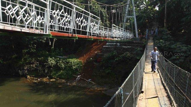 Sejumlah pekerja menyelesaikan pembuatan jembatan gantung di RW 002 Kelurahan Srengseng Sawah, Jagakarsa, Jakarta Selatan, Sabtu (28/7). Pemrov DKI Jakarta bekerjasama dengan PT Wiratman dengan menggunakan dana CSR membangun jembatan permanen untuk mengganti jembatan gantung "indiana jones" yang tidak layak untuk digunakan warga. [suara.com/Muhaimin A Untung]
