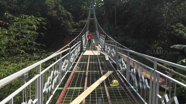 Sejumlah pekerja menyelesaikan pembuatan jembatan gantung di RW 002 Kelurahan Srengseng Sawah, Jagakarsa, Jakarta Selatan, Sabtu (28/7). Pemrov DKI Jakarta bekerjasama dengan PT Wiratman dengan menggunakan dana CSR membangun jembatan permanen untuk mengganti jembatan gantung "indiana jones" yang tidak layak untuk digunakan warga. [suara.com/Muhaimin A Untung]
