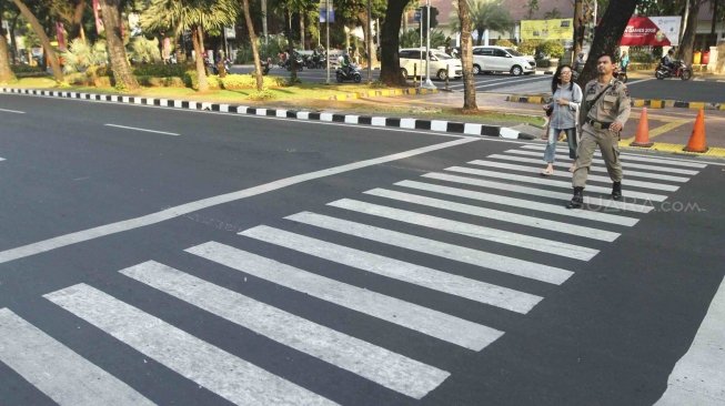 Warga menyebrang melalui Pelican Crosing di kawasan Merdeka Barat, Jakarta, Sabtu (28/7). Pemprov DKI Jakarta segera membuat pelican crossing sebagai pengganti jembatan penyeberangan orang (JPO) di Bundaran HI yang akan dirobohkan dengan alasan keindahan dan tak ramah difabel. [suara.com/Muhaimin A Untung]