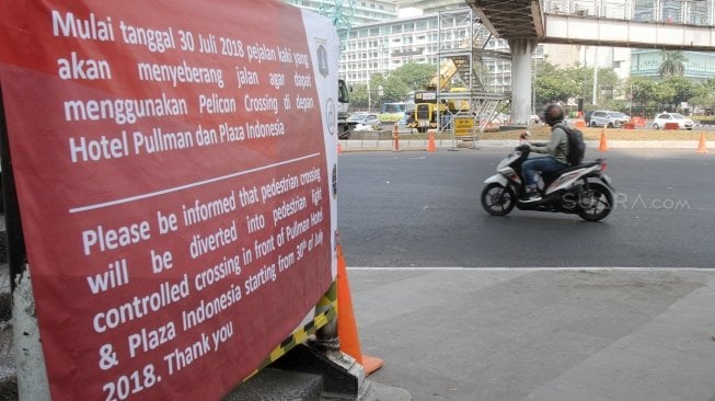 Kendaraan melintasi Jembatan Penyeberangan Orang (JPO) Bunderan Hotel Indonesia, Jakarta, Senin (30/7). Jembatan penyeberangan orang di kawasan Bundara Hotel Indonesia, hari ini ditutup dan akan dibongkar sehingga tak bisa dipakai lagi. Sebagai gantinya, pejalan kaki bisa menggunakan pelican crossing yang sudah dibuat sebagai tempat penyeberangan sementara.[Suara.com/Oke Dwi Atmaja].