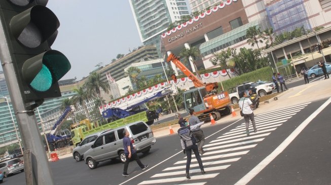 Pejalan kaki sedang menyebrang di pelican crossing dikawasan Thamrin, Jakarta, Senin (30/7). Pelican crossing dikawasan Thamrin sudah bisa di gunakan sebagai pengganti JPO yang akan dibongkar. [Suara.com/Oke Dwi Atmaja]