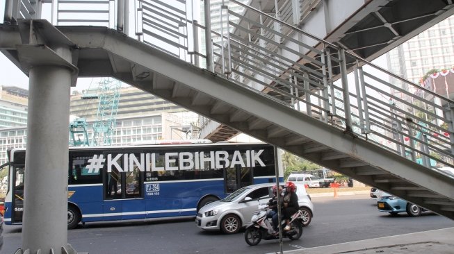 Kendaraan melintasi Jembatan Penyeberangan Orang (JPO) Bunderan Hotel Indonesia, Jakarta, Senin (30/7). Jembatan penyeberangan orang di kawasan Bundara Hotel Indonesia, hari ini ditutup dan akan dibongkar sehingga tak bisa dipakai lagi. Sebagai gantinya, pejalan kaki bisa menggunakan pelican crossing yang sudah dibuat sebagai tempat penyeberangan sementara.[Suara.com/Oke Dwi Atmaja].