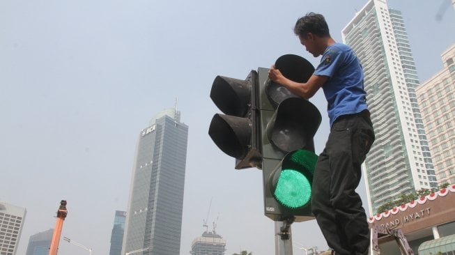 Pejalan kaki sedang menyebrang di pelican crossing dikawasan Thamrin, Jakarta, Senin (30/7). Pelican crossing dikawasan Thamrin sudah bisa di gunakan sebagai pengganti JPO yang akan dibongkar. [Suara.com/Oke Dwi Atmaja]