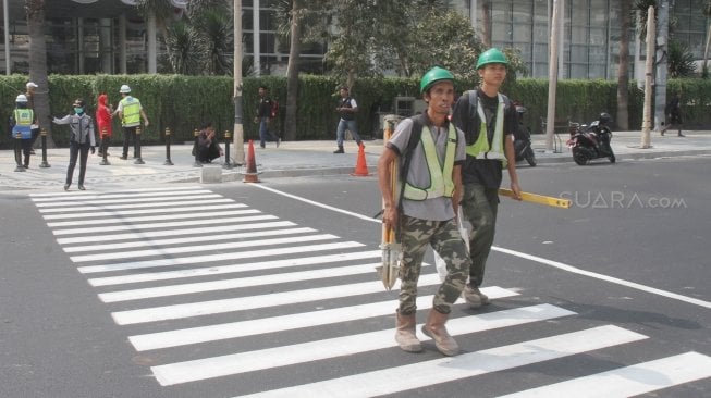 Pejalan kaki sedang menyebrang di pelican crossing dikawasan Thamrin, Jakarta, Senin (30/7). Pelican crossing dikawasan Thamrin sudah bisa di gunakan sebagai pengganti JPO yang akan dibongkar. [Suara.com/Oke Dwi Atmaja]