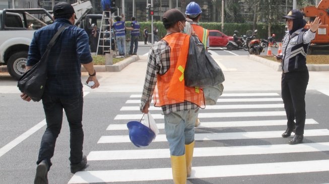 Pejalan kaki sedang menyebrang di pelican crossing dikawasan Thamrin, Jakarta, Senin (30/7). Pelican crossing dikawasan Thamrin sudah bisa di gunakan sebagai pengganti JPO yang akan dibongkar. [Suara.com/Oke Dwi Atmaja]