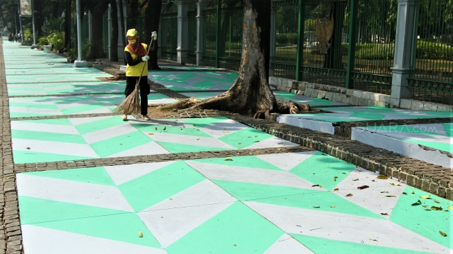 Warga melintas di Trotoar kawasan Monumen Nasional yang sudah di cat, Jakarta, Selasa (31/7). Pengecatan trotoar atau fasilitas pejalan kaki ini untuk mempercantik kawasan silang Monas dalam menyambut pagelaran Asian Games 2018 yang akan berlangsung Agustus hingga September 2018 mendatang.[suara.com/Muhaimin A Untung]