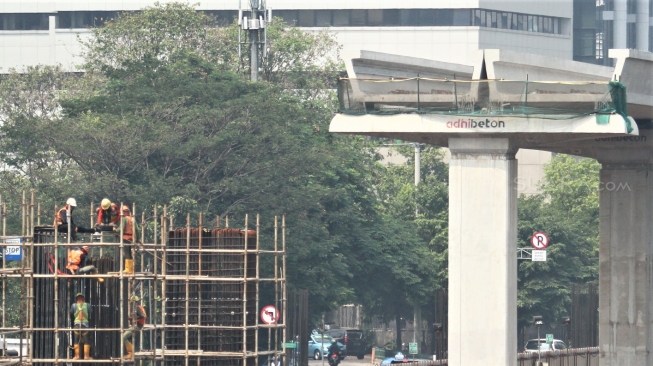 Pekerja menyelesaikan proyek light rail transit atau LRT yang melintas di Jl Rasuna Said, Jakarta, Selasa (31/7). Kereta ringan Jabodebek ditargetkan beroperasi pada Mei 2019 yang bakal melintasi tiga rute atau lintasan, yakni dari Cibubur menuju Cawang, Bekasi Timur menuju Cawang, dan Cawang menuju Dukuh  Atas belum dapat dipakai saat perhelatan akbar Asian Games. [suara.com/Muhaimin A Untung].