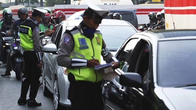 Polisi memberhentikan mobil berplat genap yang melintas pada tanggal ganjil di kawasan pancoran, Jl MT Haryono, Jakarta, Rabu (1/8). Aturan sistem perluasan lalu lintas ganjil-genap di sejumlah ruas jalan protokol Jakarta jelang asian games diberlakukan penilangan per tanggal 1 Agustus, bagi pengendara yang melanggar akan dikenai sanksi sebesar Rp 500 ribu.[suara.com/Muhaimin A Untung]