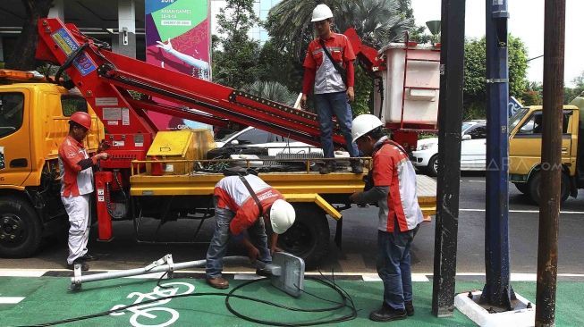 Sejumlah petugas membongkar tiang lampu jalan di kawasan pedestrian GBK, Jakarta, Rabu (1/8). Pembongkaran tiang  tersebut karena berdiri ditengah jalur pedestrian dan menggangu para pengendara sepeda.[suara/Muhaimin A Untung]