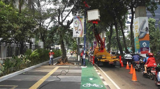 Sejumlah petugas membongkar tiang lampu jalan di kawasan pedestrian GBK, Jakarta, Rabu (1/8). Pembongkaran tiang  tersebut karena berdiri ditengah jalur pedestrian dan menggangu para pengendara sepeda.[suara/Muhaimin A Untung]