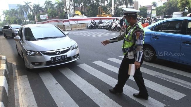 Polisi memberhentikan mobil berplat genap yang melintas pada tanggal ganjil di kawasan pancoran, Jl MT Haryono, Jakarta, Rabu (1/8). Aturan sistem perluasan lalu lintas ganjil-genap di sejumlah ruas jalan protokol Jakarta jelang asian games diberlakukan penilangan per tanggal 1 Agustus, bagi pengendara yang melanggar akan dikenai sanksi sebesar Rp 500 ribu.[suara.com/Muhaimin A Untung]