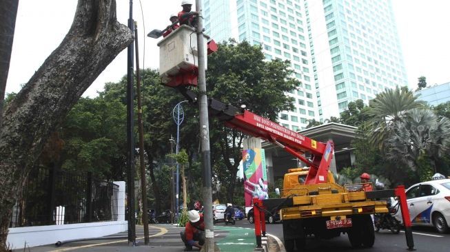 Sejumlah petugas membongkar tiang lampu jalan di kawasan pedestrian GBK, Jakarta, Rabu (1/8). Pembongkaran tiang  tersebut karena berdiri ditengah jalur pedestrian dan menggangu para pengendara sepeda.[suara/Muhaimin A Untung]