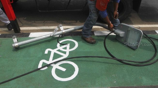 Sejumlah petugas membongkar tiang lampu jalan di kawasan pedestrian GBK, Jakarta, Rabu (1/8). Pembongkaran tiang  tersebut karena berdiri ditengah jalur pedestrian dan menggangu para pengendara sepeda.[suara/Muhaimin A Untung]