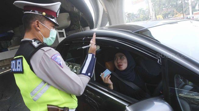 Polisi memberhentikan mobil berplat genap yang melintas pada tanggal ganjil di kawasan pancoran, Jl MT Haryono, Jakarta, Rabu (1/8). Aturan sistem perluasan lalu lintas ganjil-genap di sejumlah ruas jalan protokol Jakarta jelang asian games diberlakukan penilangan per tanggal 1 Agustus, bagi pengendara yang melanggar akan dikenai sanksi sebesar Rp 500 ribu.[suara.com/Muhaimin A Untung]