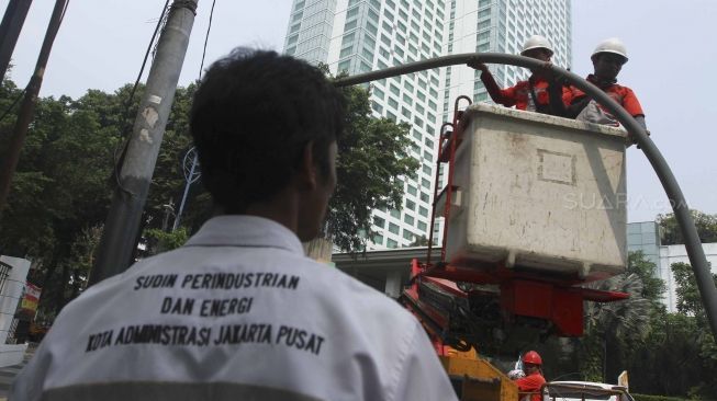 Sejumlah petugas membongkar tiang lampu jalan di kawasan pedestrian GBK, Jakarta, Rabu (1/8). Pembongkaran tiang  tersebut karena berdiri ditengah jalur pedestrian dan menggangu para pengendara sepeda.[suara/Muhaimin A Untung]