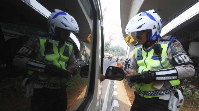 Polisi memberhentikan mobil berplat genap yang melintas pada tanggal ganjil di kawasan pancoran, Jl MT Haryono, Jakarta, Rabu (1/8). Aturan sistem perluasan lalu lintas ganjil-genap di sejumlah ruas jalan protokol Jakarta jelang asian games diberlakukan penilangan per tanggal 1 Agustus, bagi pengendara yang melanggar akan dikenai sanksi sebesar Rp 500 ribu.[suara.com/Muhaimin A Untung]