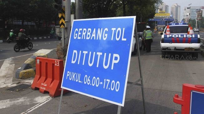 Dirlantas Polda Metro Jaya bersama Dinas Perhubungan DKI Jakarta menjaga pintu gerbang tol yang ditutup di Tol Slipi 2, Jakarta, Rabu (1/8). Penutupan pintu tol secara permanen di 19 pintu tol tersebut demi kelancaran transportasi penyelenggaraan Asian Games 2018 agar waktu tempuh perjalanan atlet dari wisma atlet menuju veneu cuma 30 menit. [suara.com/Muhaimin A Untung].