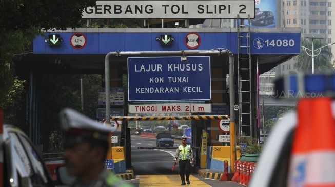 Dirlantas Polda Metro Jaya bersama Dinas Perhubungan DKI Jakarta menjaga pintu gerbang tol yang ditutup di Tol Slipi 2, Jakarta, Rabu (1/8). Penutupan pintu tol secara permanen di 19 pintu tol tersebut demi kelancaran transportasi penyelenggaraan Asian Games 2018 agar waktu tempuh perjalanan atlet dari wisma atlet menuju veneu cuma 30 menit. [suara.com/Muhaimin A Untung].